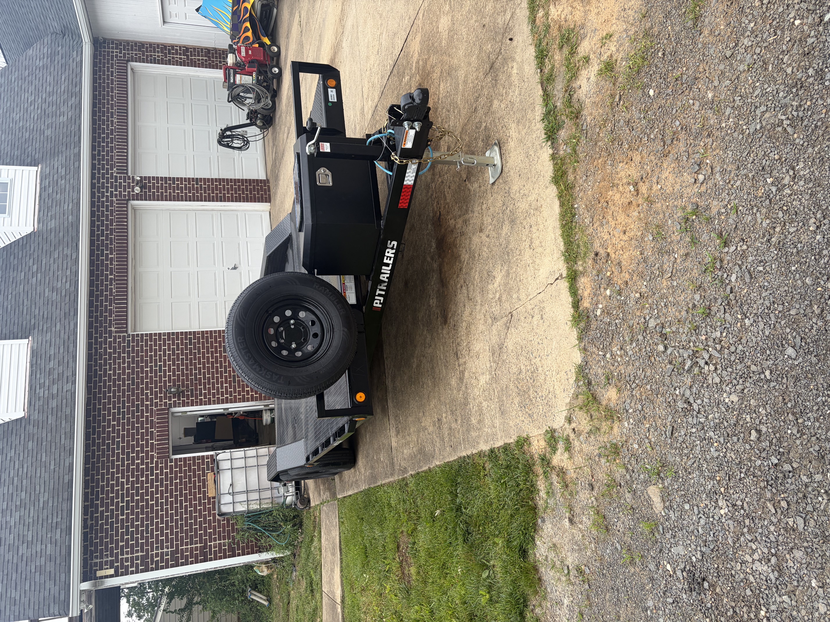 PJ Trailers car hauler front view showing coupler, jack, toolbox, and spare tire